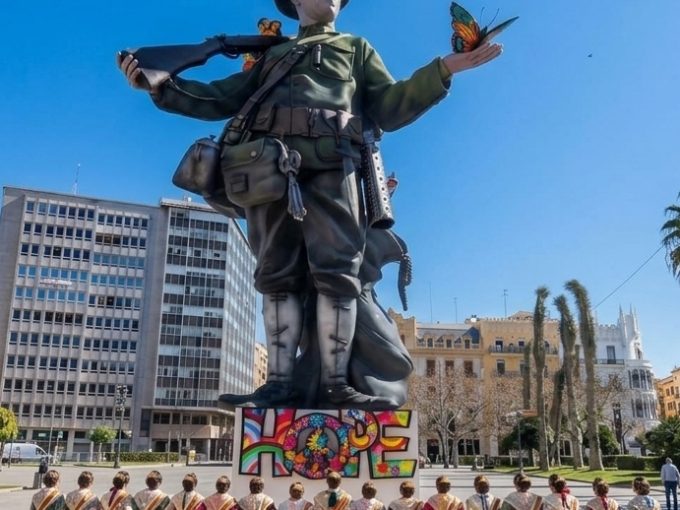 Cabisuar Valencia colabora con las Fallas: falla monumental con la figura de un soldado sosteniendo una mariposa junto al cartel "HOPE", con falleras vestidas de traje tradicional en primer plano